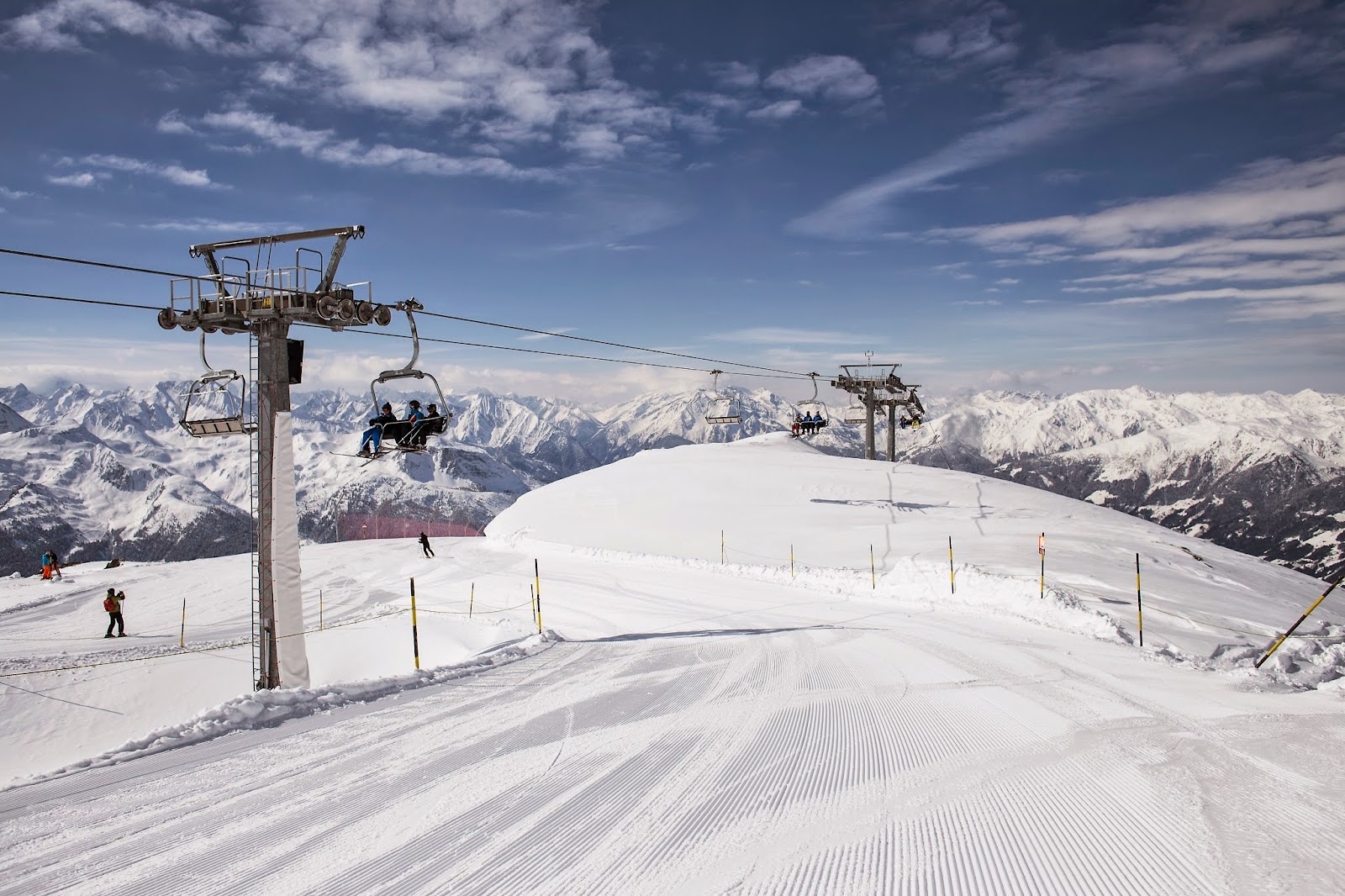Skiers on a wide groomed piste in the Zillertal Arena above Gerlos