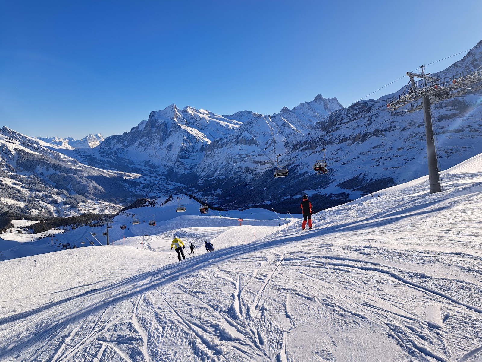 Skiers on gentle pistes above Wengen with big mountain views